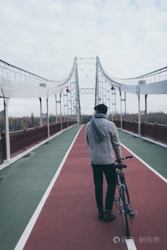 骑自行车的时尚男子的背景色站在行人天桥上照片-正