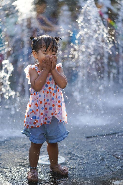 6月20日,小女孩在北京华熙live·五棵松商业街区一处喷泉戏水.