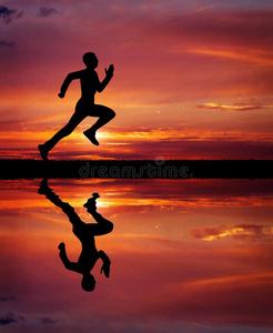 炽热的火山灰夕阳下炽热的背景上奔跑的人的剪影.照片