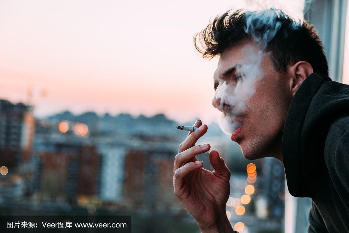日落时分,一个年轻人在阳台上抽烟