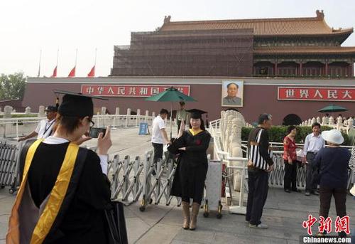 5月13日,两名身着学士服,头戴学士帽的90后大学生在北京天安门前拍