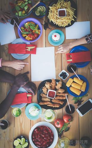 顶视图的一群人在一起时坐在木桌吃饭.在桌子上的食物.人们吃快餐