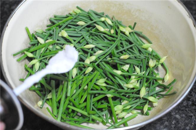 沥干水分的韭菜花切成段,放入到一个大盆中,加入适量的食用盐,用筷子