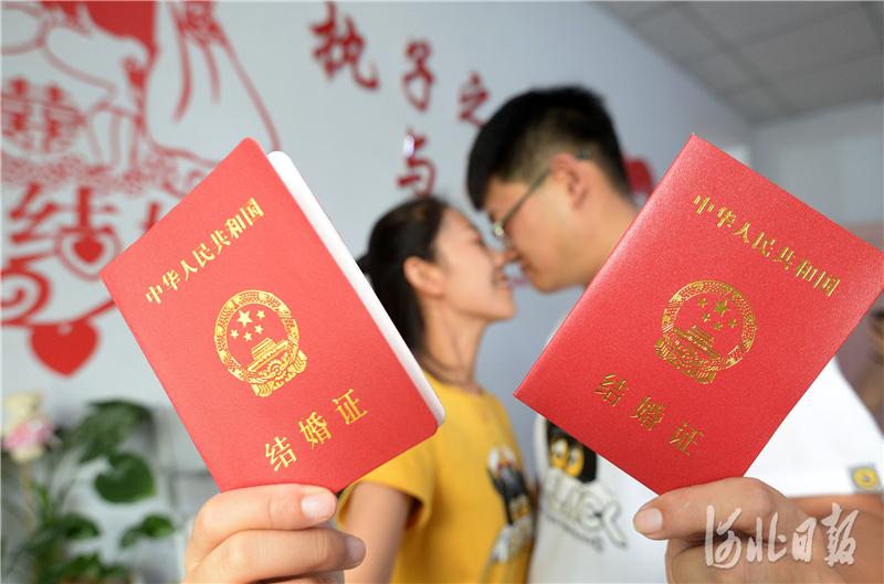 一对新人在邯郸市丛台区民政局婚姻登记处展示刚刚领取的结婚证