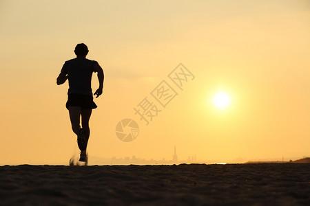 一个在日落时海滩上奔跑的人背影其景是地平线图片素材