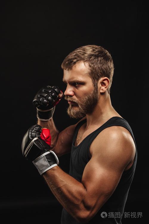 戴着手套在深色背景上的竞技胡子的拳击手