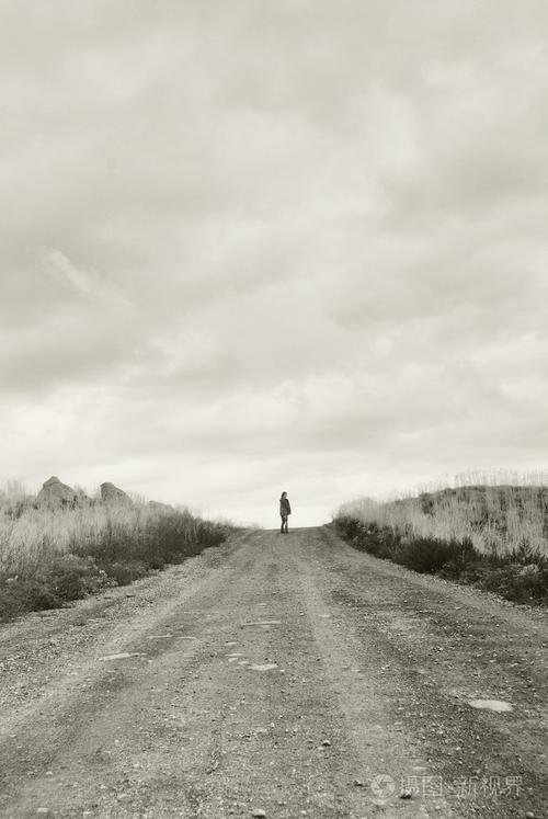 孤独的人站在遥远的道路上单色