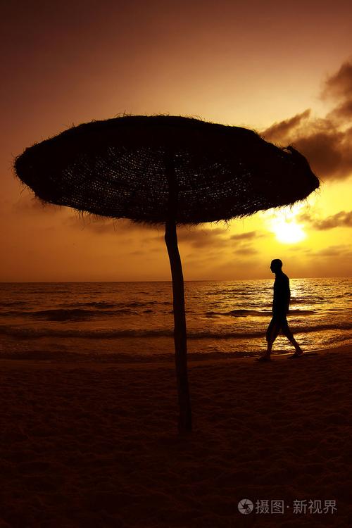在海上日落一个人走在沙滩上