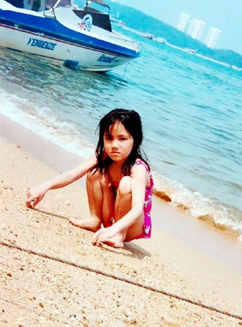 这是1998年邓紫棋七岁时的照片,她在海边的游泳池里蹲着玩.