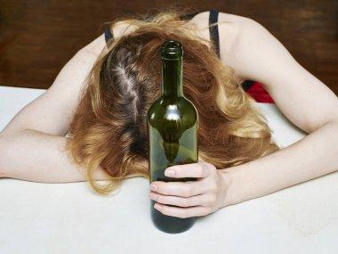 一个悲伤的女人把头靠在桌子上喝着杯子里的酒靠近点