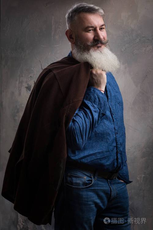 一个留着胡子和胡子的中年男子的肖像在黑暗的背景下随意摆姿势有选择