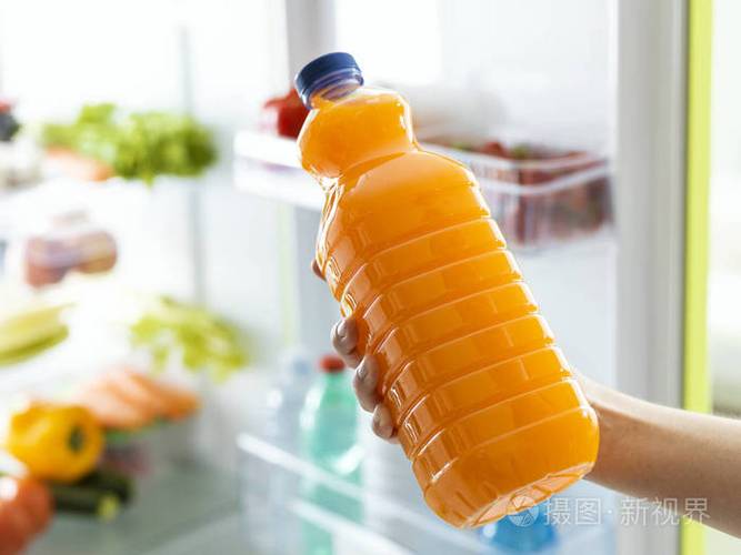 从冰箱里拿出一瓶新鲜橙汁的女人, 健康饮料概念