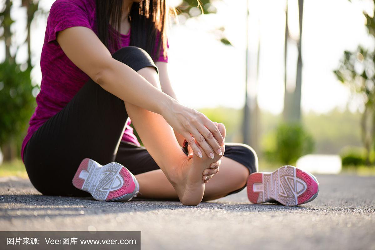 年轻女子在锻炼时按摩她疼痛的脚.跑步运动与运动损伤概念.