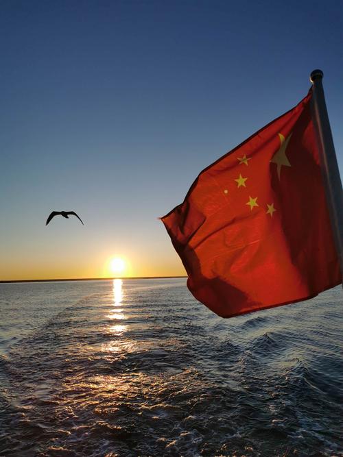 鲜艳的五星红旗也随着红日的升起在湖面上迎风飘扬.