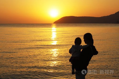母亲和日落海滩上的小女儿剪影