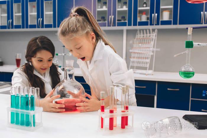 两个小孩在实验室的外衣里学习化学, 在学校的实验室里.