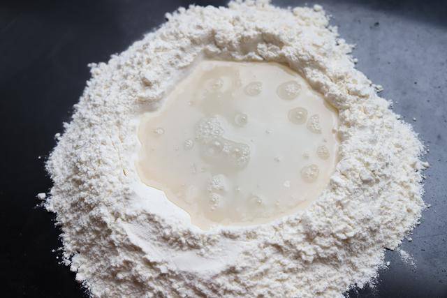 2,称出200克面粉,普通中筋面粉即可,倒在台面上,中间开窝,加入酵母水