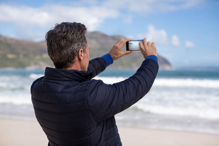 海边用手机拍照的男士