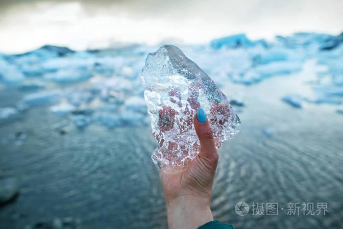 旅游女孩手里拿着一块冰块它站在冰川上靠近冰山