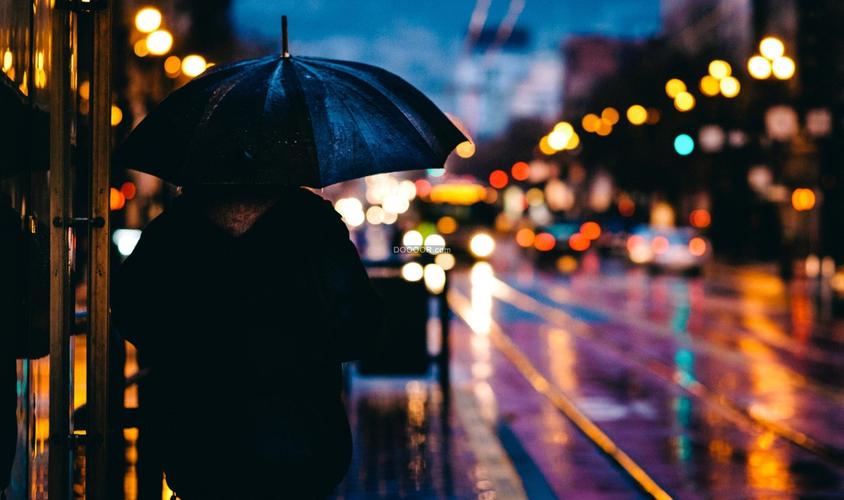 01442_下雨天一个女生撑着雨伞走在灯火阑珊的街头.jpg