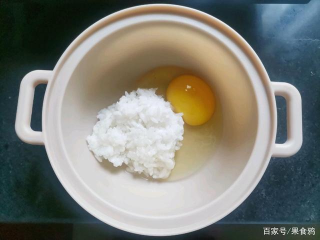 2,碗中磕入一个鸡蛋,把前一天晚上吃剩下的 米饭舀一勺放入碗中.