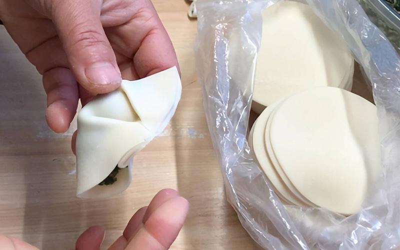 第六步:在饺子皮上放上馅儿,然后从两边对称着往中间捏出褶子,这样包