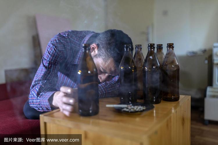 年轻悲伤的醉酒男子喝啤酒和酒精感到浪费,孤独和绝望的痛苦和情绪