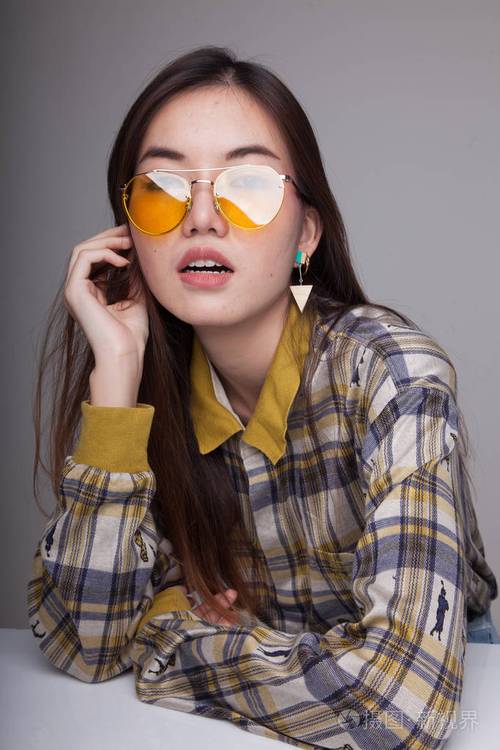 美丽的年轻亚洲妇女用黄色太阳镜