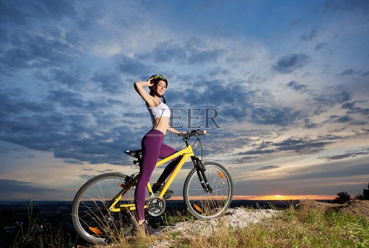 年轻的自行车女骑在山顶与美丽的风景日落照片摄影图片