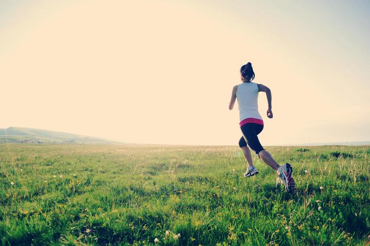 日落时分年轻健康的女子在的草地上慢跑励志奋斗奔跑努力运动健身户外