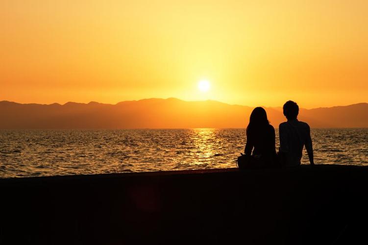 沿着大海和一对夫妇的剪影的日落