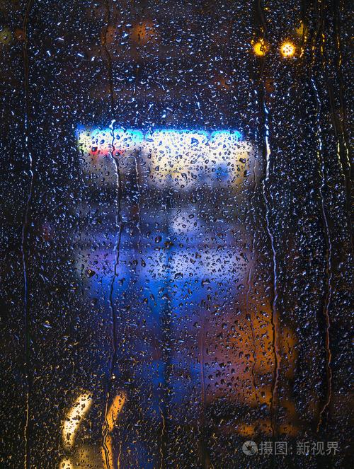 城市夜景灯光的玻璃窗上的雨点