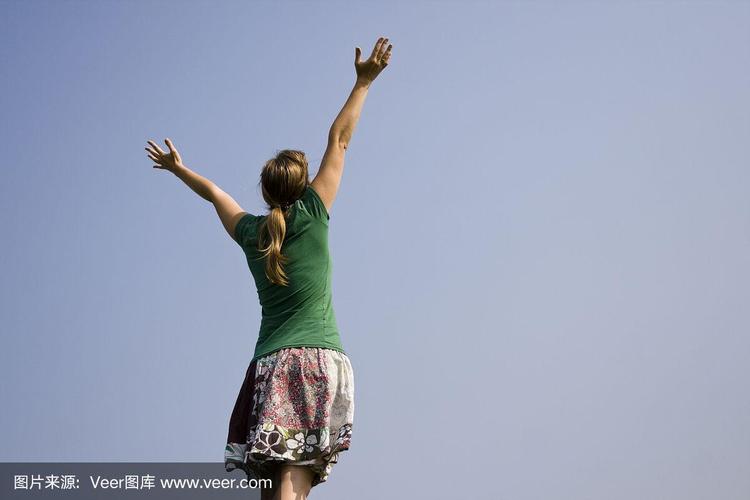 年轻女子举起双手望向天空.