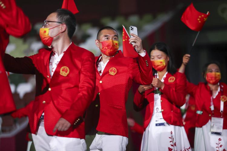 中国奥运会代表团成员身穿红白配色入场服,手挥五星红旗,由朱婷和赵帅