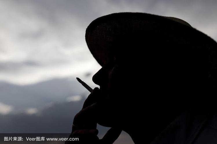 在日落的背景上,一个男人吸烟的剪影