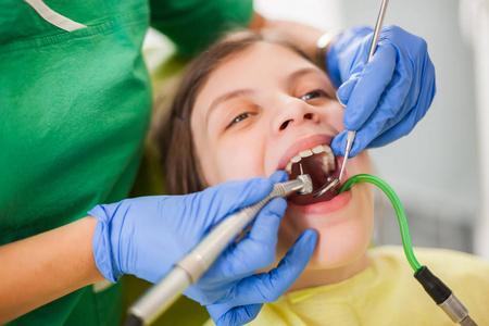 牙医正在修理一个小女孩的牙齿.照片