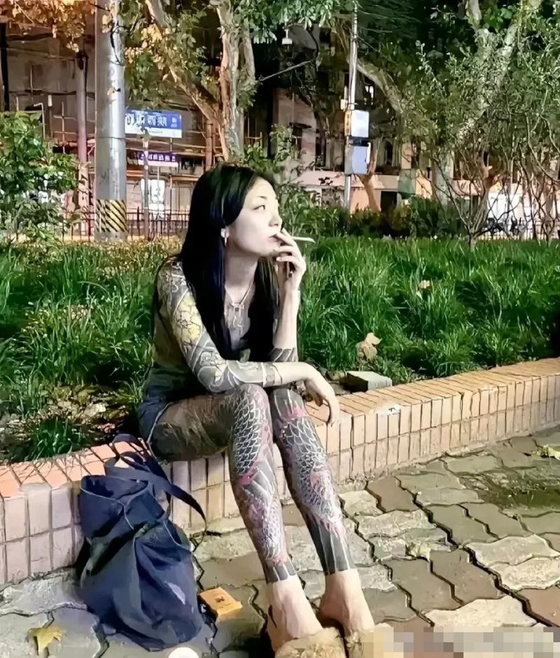 照片上是一个纹身的女人,坐在街边抽烟的情景,这个女人的装扮真是吓人