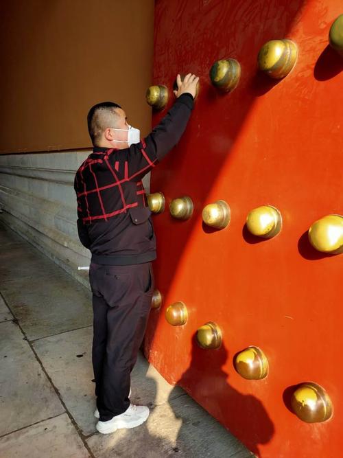 在故宫博物院的大门口,请盲人朋友朱云龙抚摸门钉,增添了新鲜感受.