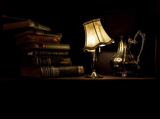 黑色古董复古古玩店夜晚桌上的老式打印机厚本书和欧式台灯宣传照背景