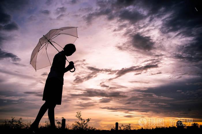 照片 女孩悲伤剪影风格独自行走户外和雨伞在她的手与多云的天空和