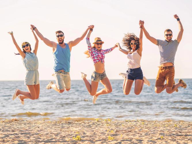 夏季一群快乐的年轻人在沙滩上跳起来青春励志奋斗奋斗