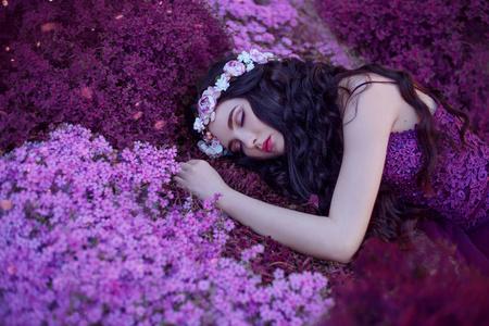 一个温柔优雅的女孩睡在神奇的紫色花坛上, 一个梦幻般的美丽与长长的