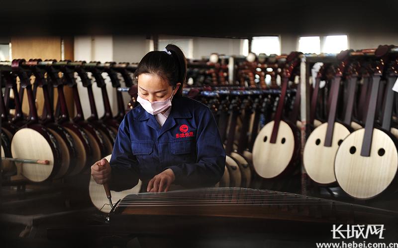 工人在肃宁县一家民族乐器厂生产车间为古筝调音.苑立伟 摄