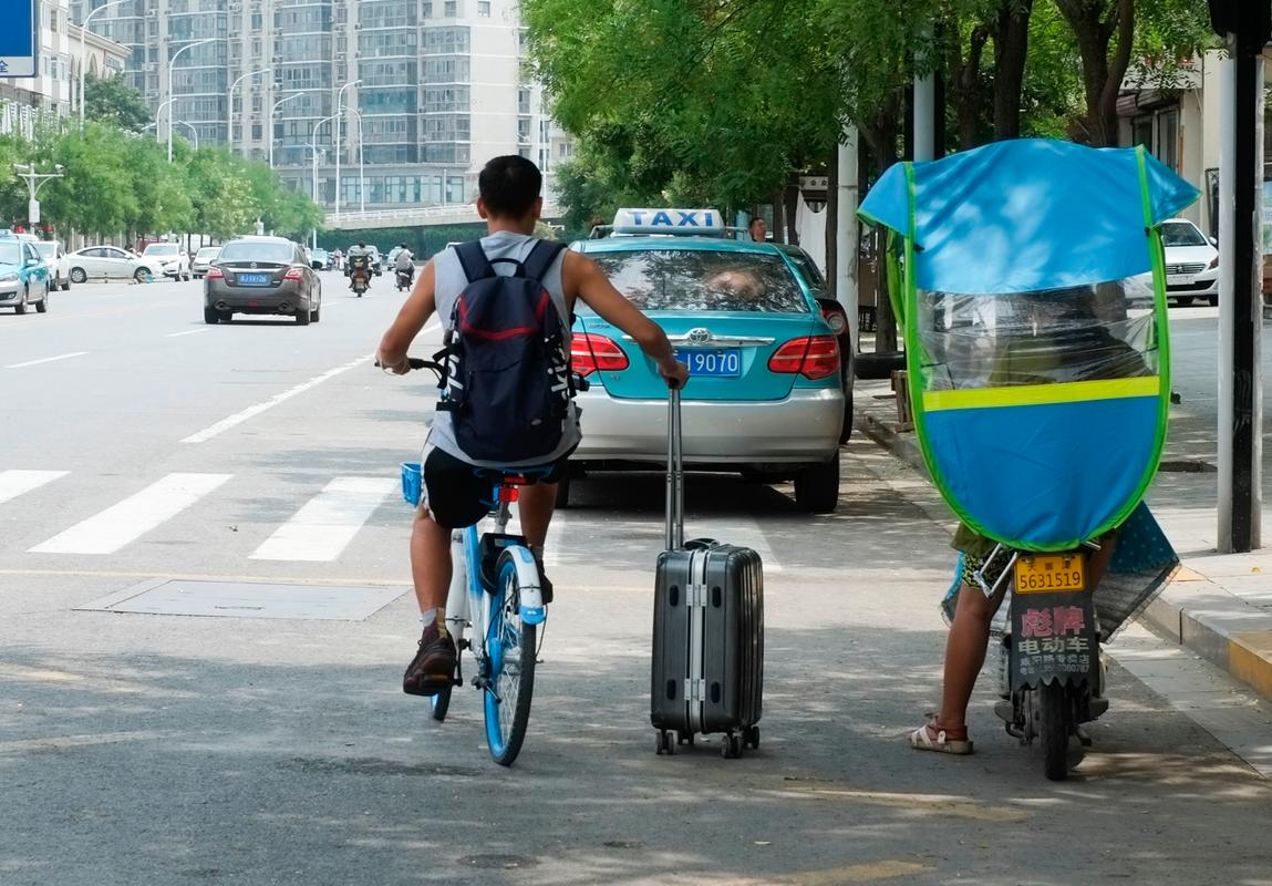 天津火车站外 多名年轻人骑单车拉行李箱 场面有趣