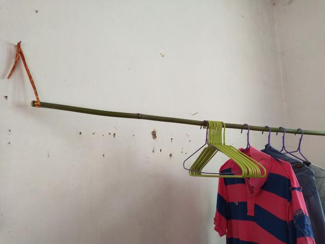 没地方晒衣服,熊老师就去砍了一根竹子,用绳子吊在墙角晾晒衣服.