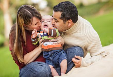 快乐的混合种族父母在亲吻着自己的孩子图片素材