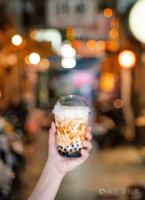 在台湾夜市年轻女孩拿着一杯红糖味的木薯珍珠泡奶茶展示特写博克