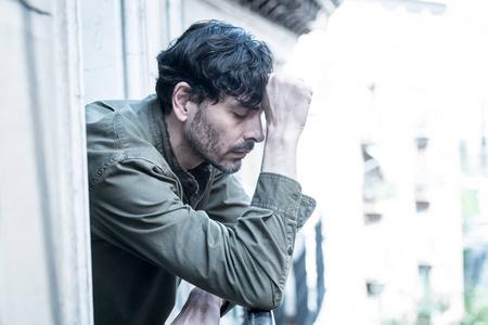 闭上悲伤沮丧的男人的肖像看窗外在家庭中遭受抑郁症和孤独感的心理