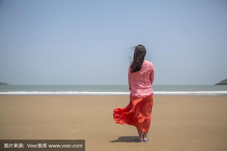 女孩站在沙滩上,面朝大海