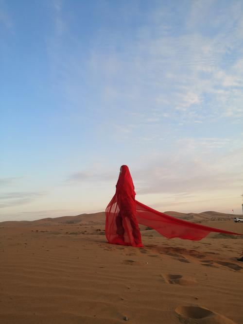 一袭红裙的阿宝给荒芜的沙漠增添了一道靓丽的风景